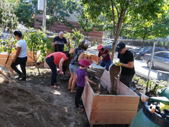 Children and adults volunteering in the garden, building and filling raised beds